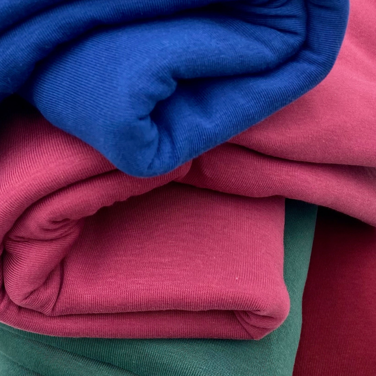 Stack of folded clothes in blue, pink, and green.